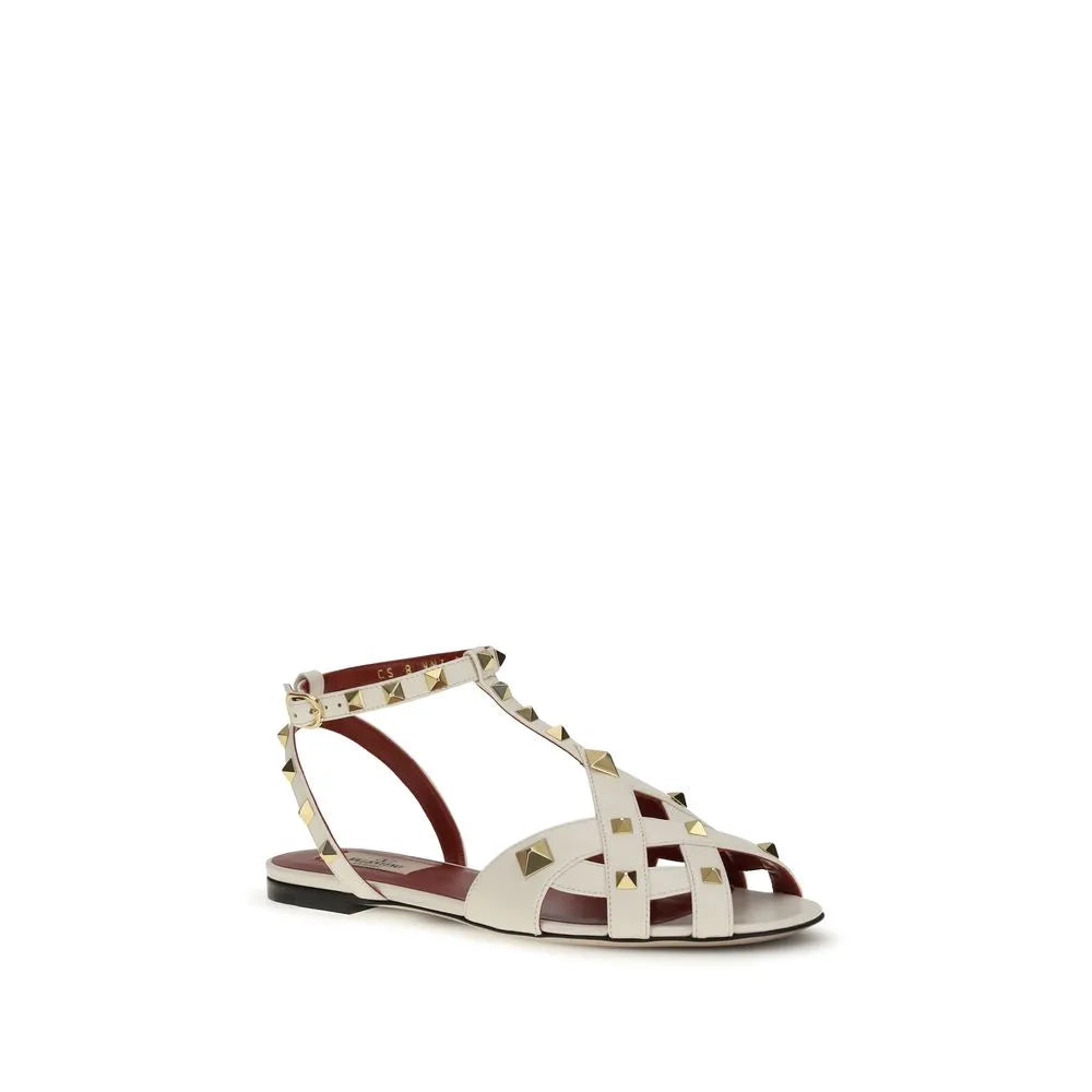 Valentino Garavani Studdy flat sandals in off-white goatskin with gold pyramid studs and adjustable ankle strap.
