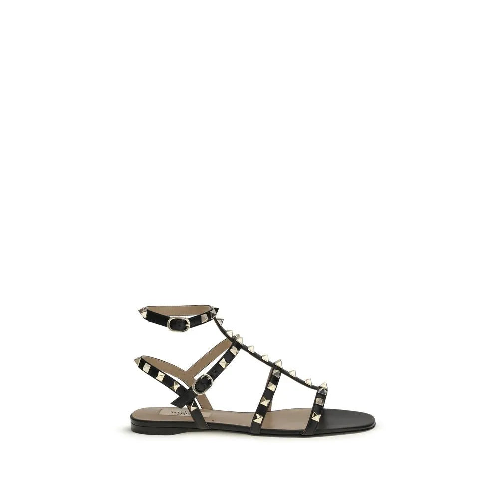 Black calf leather Valentino Garavani Rockstud flat sandals with gold studs and adjustable ankle strap.