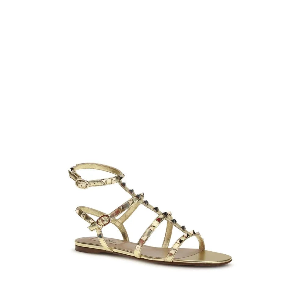 Gold laminated calf leather flat sandals with platinum Rockstuds and adjustable buckle strap.