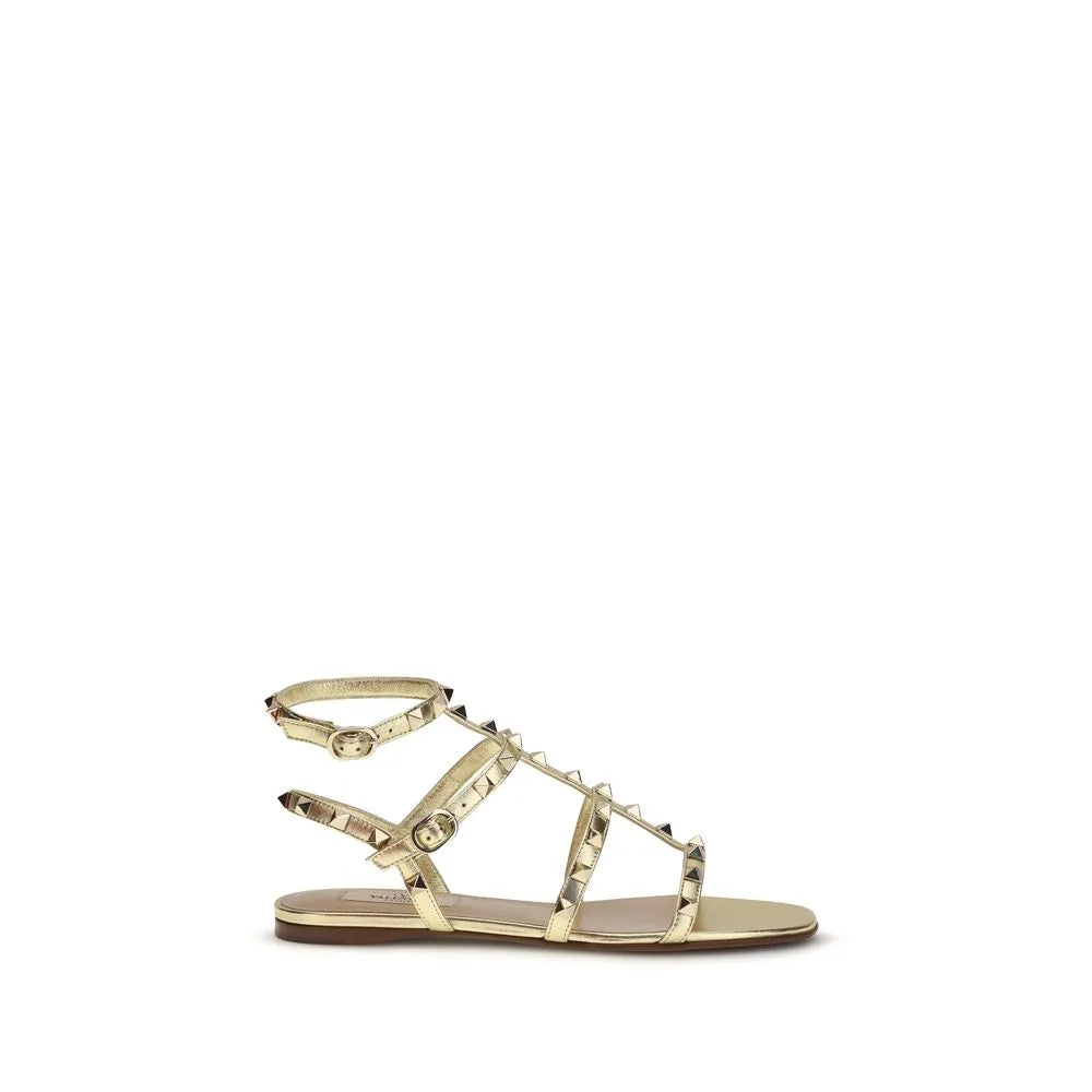 Valentino Garavani gold laminated calfskin Rockstud flat sandals with platinum studs and ankle strap.