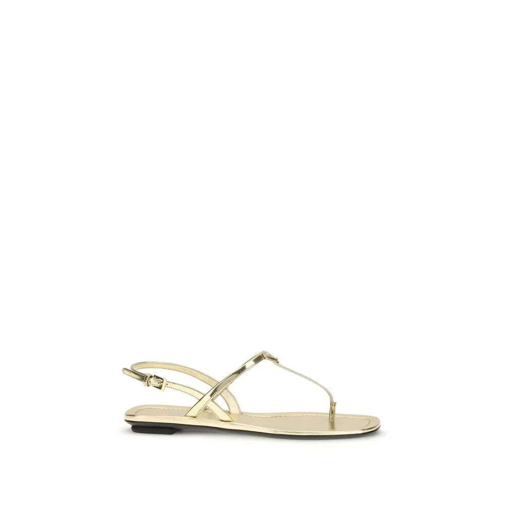 Shiny gold patent leather flat sandals with thin thong strap and adjustable ankle buckle.