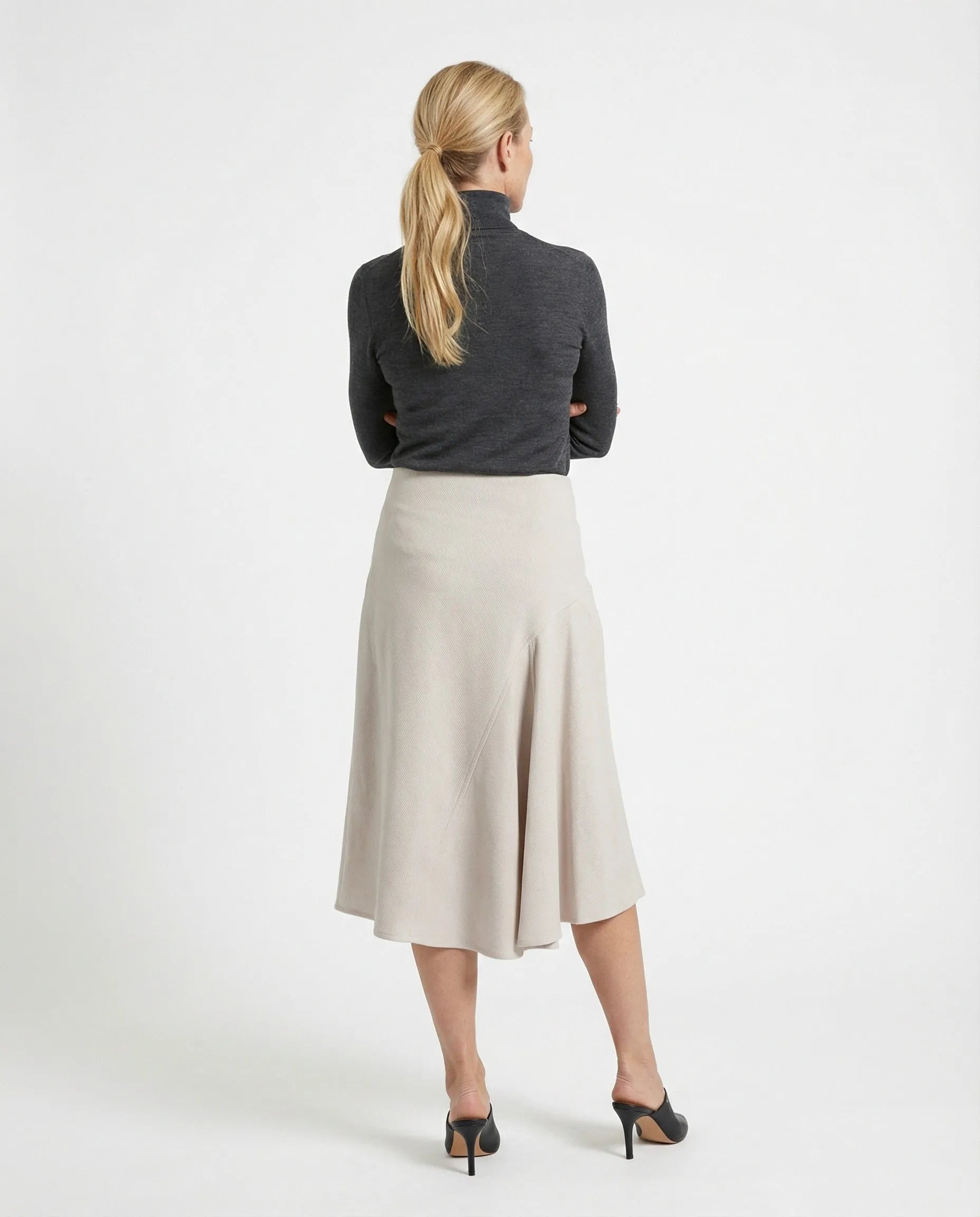 Light beige cotton blend midi skirt with a tailored A-line flare, worn by a woman from the back.