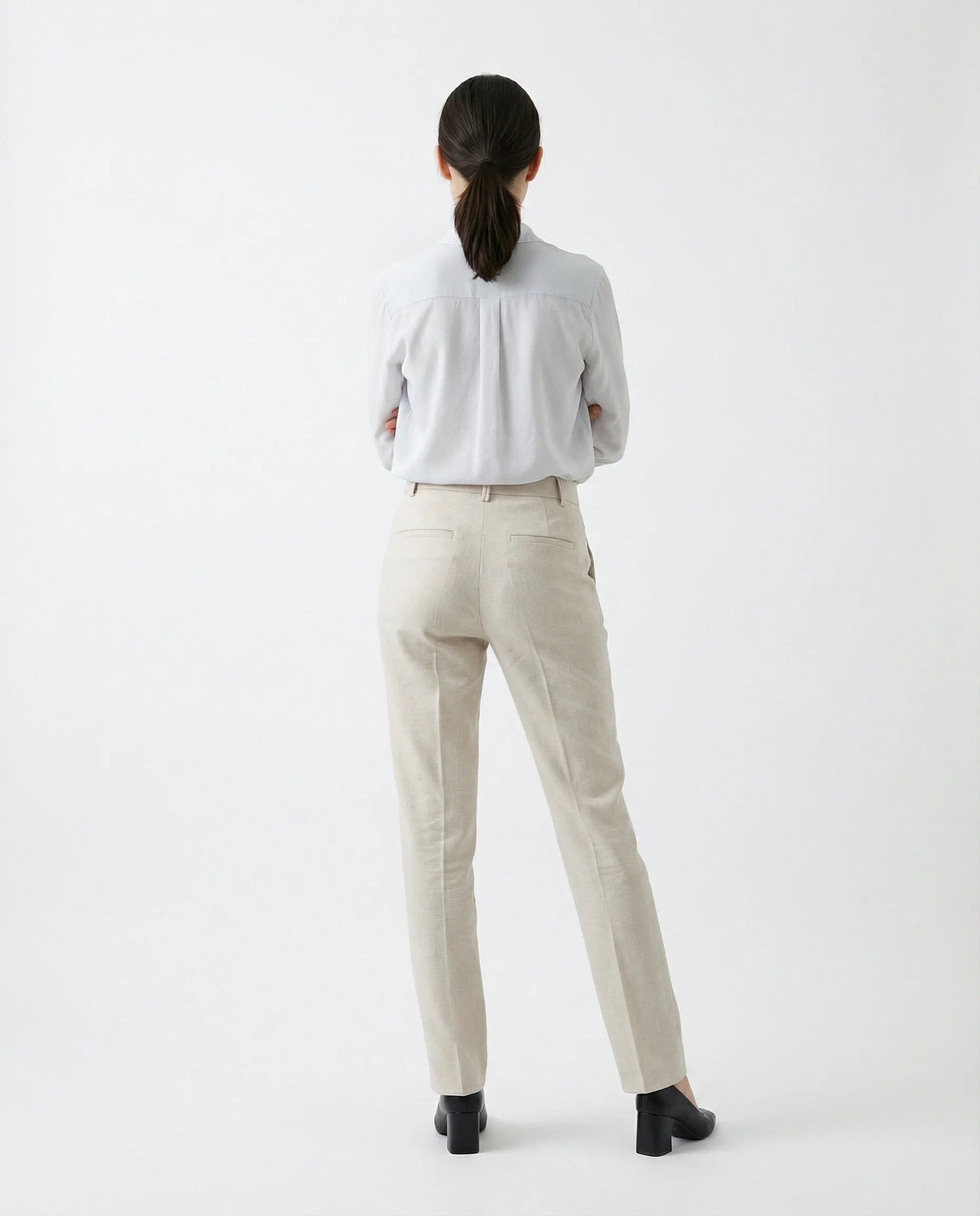 Tailored light beige cotton-blend pants on a woman, styled with a light shirt and black heels.